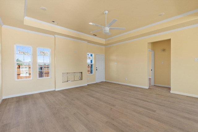 empty room featuring a tray ceiling, ornamental molding, light hardwood / wood-style floors, and ceiling fan