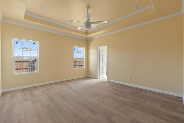 spare room with a raised ceiling, ornamental molding, ceiling fan, and light hardwood / wood-style flooring