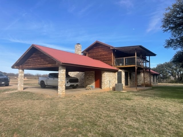 back of house with central AC, a yard, and a carport