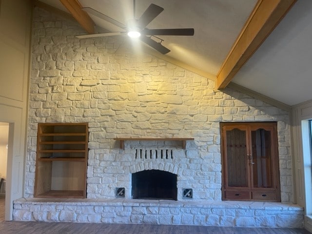 interior space featuring ceiling fan, hardwood / wood-style floors, vaulted ceiling with beams, and a fireplace