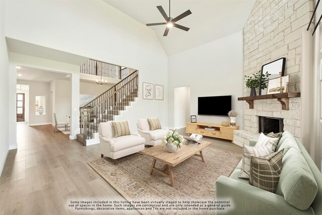 living room with ceiling fan, a fireplace, high vaulted ceiling, and light wood-type flooring