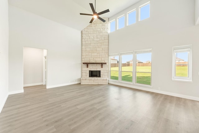 unfurnished living room featuring a fireplace, light wood-type flooring, high vaulted ceiling, and a wealth of natural light