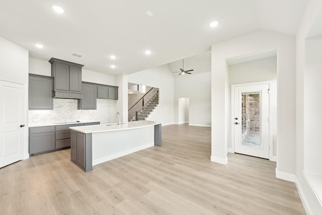 kitchen featuring light wood-type flooring, a center island with sink, and black cooktop