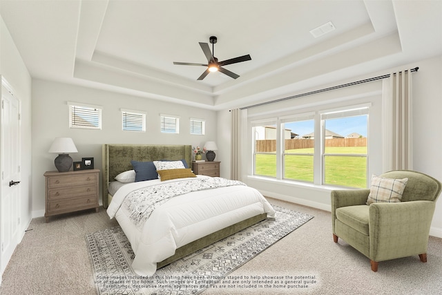 carpeted bedroom with ceiling fan and a raised ceiling