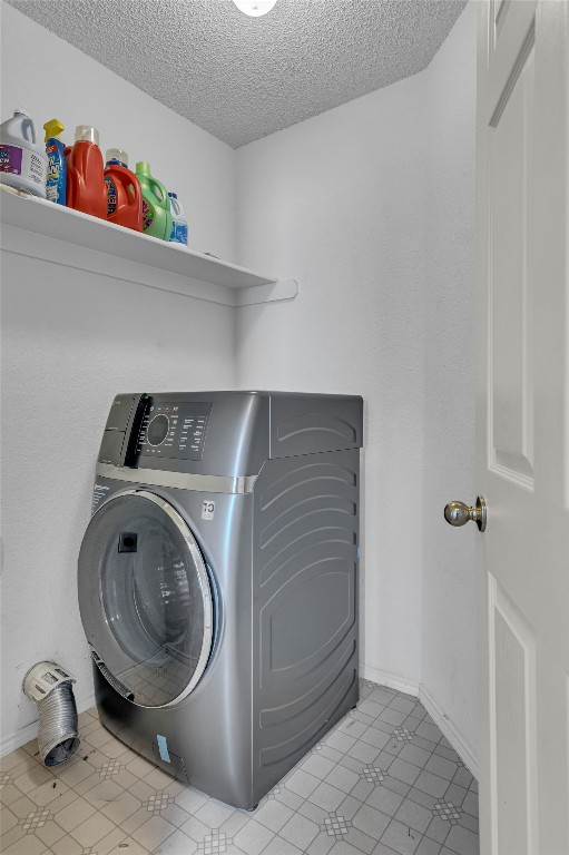 washroom with a textured ceiling, washer / clothes dryer, and light tile floors