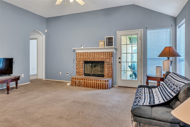 living room with light colored carpet, vaulted ceiling, ceiling fan, and a brick fireplace