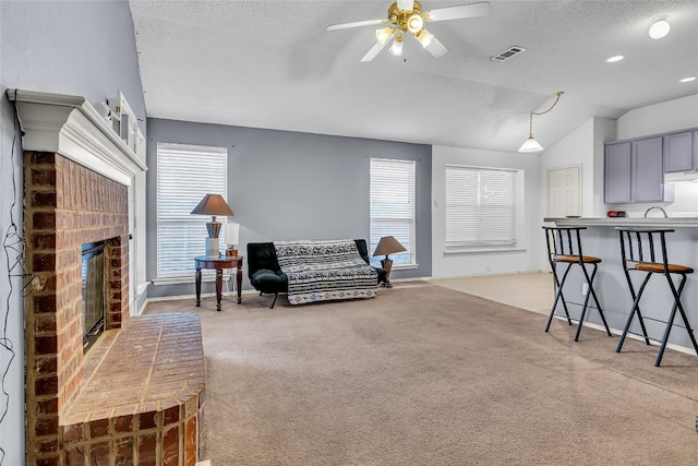 living room with light colored carpet, a brick fireplace, ceiling fan, and vaulted ceiling