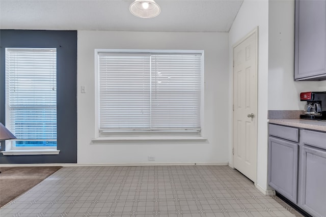 doorway to outside featuring vaulted ceiling and light tile flooring