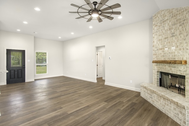 unfurnished living room featuring a fireplace, dark hardwood / wood-style floors, ceiling fan, and vaulted ceiling