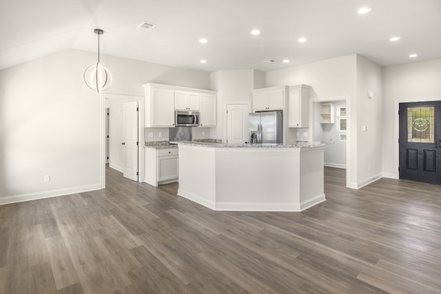 kitchen featuring dark wood-type flooring, appliances with stainless steel finishes, white cabinetry, hanging light fixtures, and a kitchen island with sink