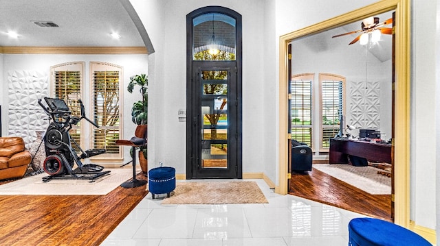 tiled entryway featuring ornamental molding, ceiling fan, and a textured ceiling