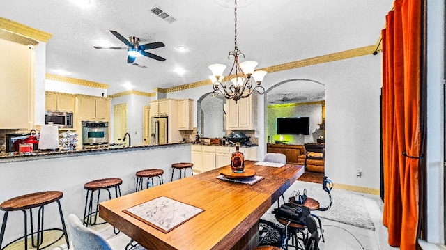 dining space featuring ceiling fan with notable chandelier and ornamental molding