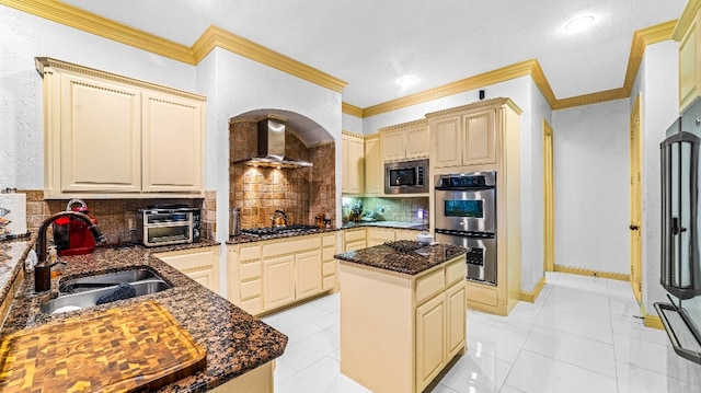 kitchen with sink, tasteful backsplash, a center island, and wall chimney range hood