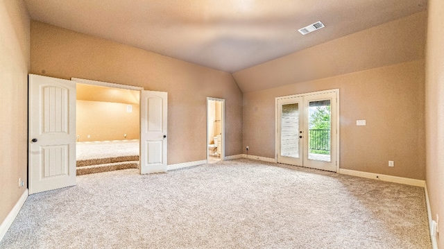 unfurnished bedroom with lofted ceiling, french doors, light carpet, and access to exterior