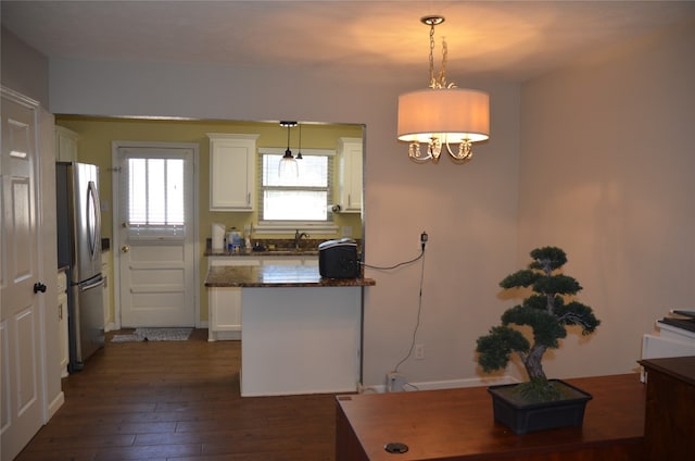 kitchen featuring stainless steel fridge, white cabinetry, and hanging light fixtures