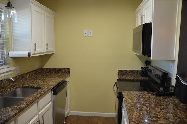 kitchen with stainless steel appliances, sink, dark stone counters, white cabinetry, and dark hardwood / wood-style floors