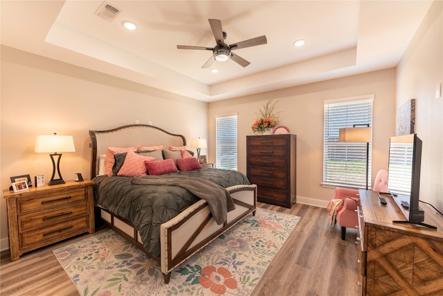 bedroom featuring ceiling fan, a raised ceiling, and hardwood / wood-style floors