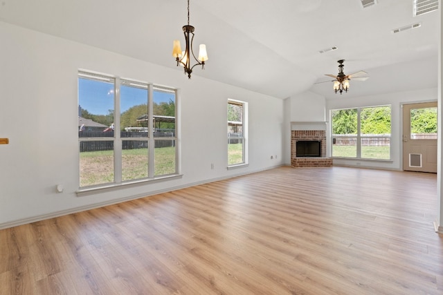 unfurnished living room with light wood-type flooring, a brick fireplace, vaulted ceiling, and ceiling fan with notable chandelier