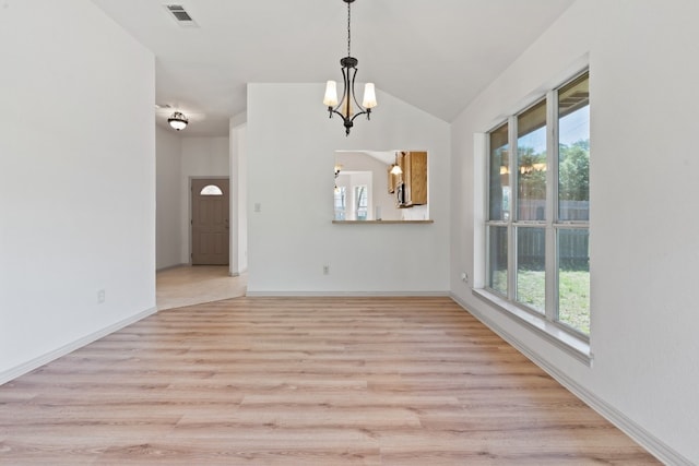 spare room featuring lofted ceiling, a chandelier, and light hardwood / wood-style floors