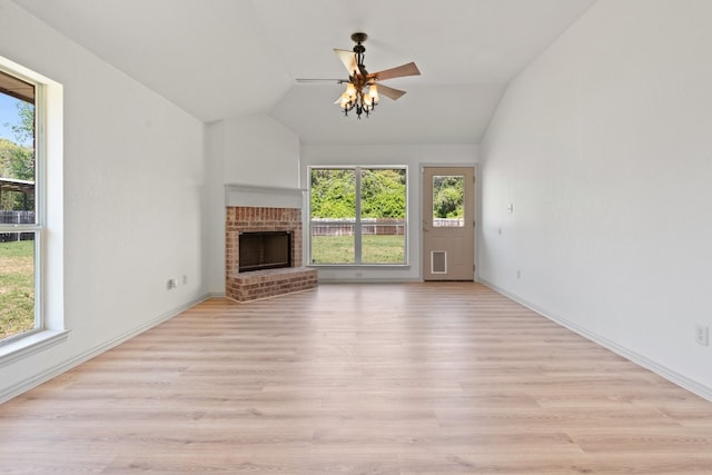 unfurnished living room featuring ceiling fan, a wealth of natural light, a fireplace, and light hardwood / wood-style floors