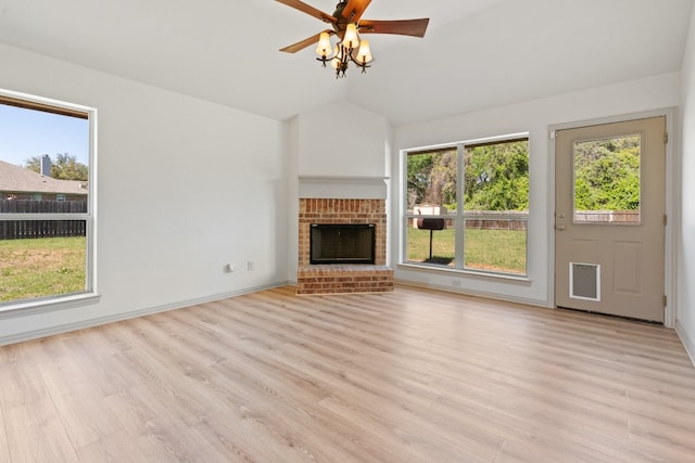 unfurnished living room featuring light wood-type flooring, a brick fireplace, and a healthy amount of sunlight