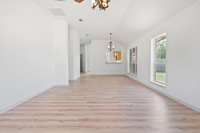 unfurnished living room with a wealth of natural light, an inviting chandelier, and light wood-type flooring