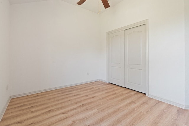 unfurnished bedroom featuring lofted ceiling, light hardwood / wood-style floors, ceiling fan, and a closet