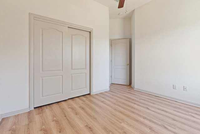 unfurnished bedroom with ceiling fan, light wood-type flooring, and a closet