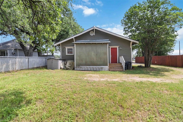 rear view of house featuring a yard and a shed