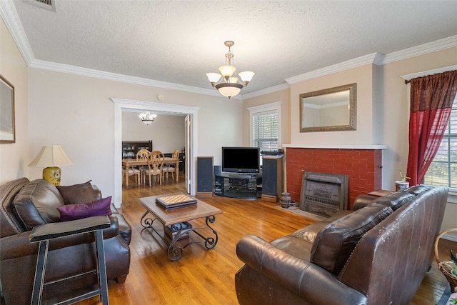 living room with ornamental molding, a healthy amount of sunlight, hardwood / wood-style flooring, and a brick fireplace