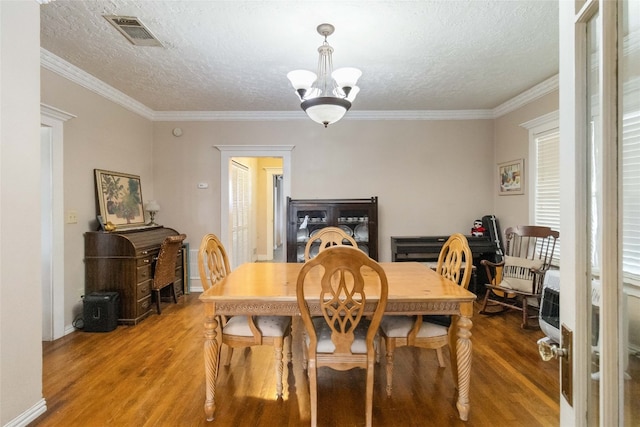 dining area featuring ornamental molding, a textured ceiling, a chandelier, and wood-type flooring