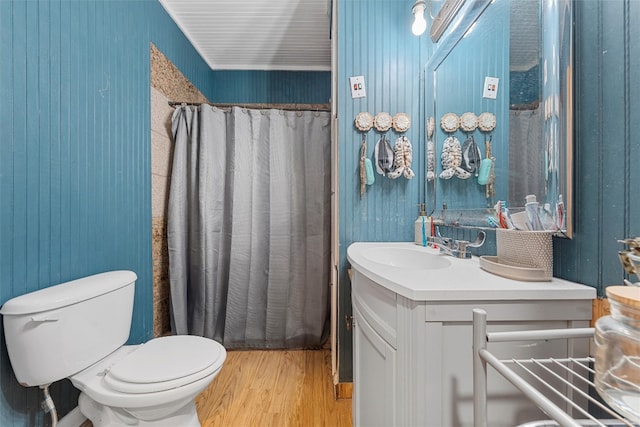 bathroom with wooden walls, wood-type flooring, vanity, and toilet