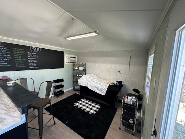 bedroom featuring lofted ceiling, a wall unit AC, light hardwood / wood-style floors, and ornamental molding