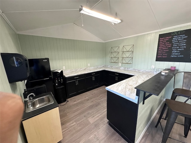 kitchen featuring a breakfast bar, sink, light wood-type flooring, ornamental molding, and kitchen peninsula