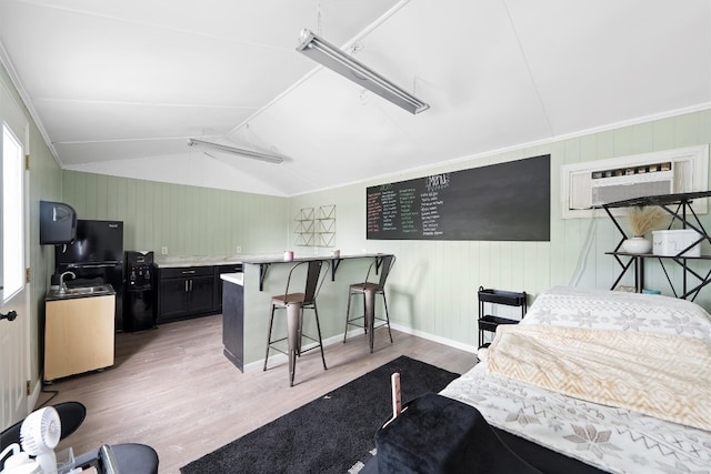 interior space with lofted ceiling, a wall mounted AC, light wood-type flooring, black refrigerator, and ornamental molding