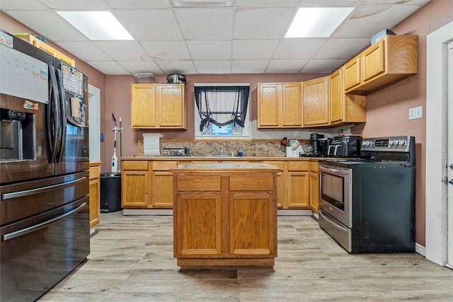 kitchen with light hardwood / wood-style flooring, black fridge with ice dispenser, electric range, a center island, and a paneled ceiling