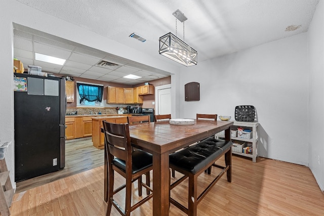 dining space featuring a notable chandelier, light hardwood / wood-style floors, and a paneled ceiling