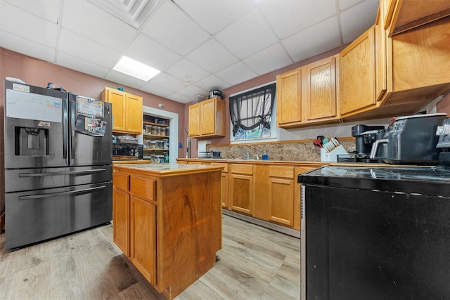 kitchen featuring a kitchen island, refrigerator with ice dispenser, a drop ceiling, and light hardwood / wood-style floors