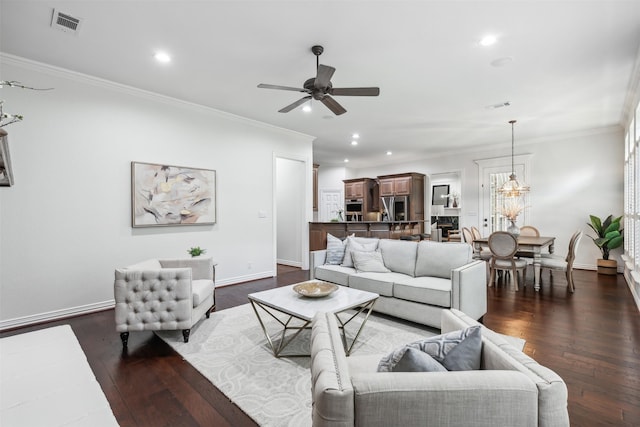 living room with ceiling fan with notable chandelier, crown molding, and dark wood-type flooring