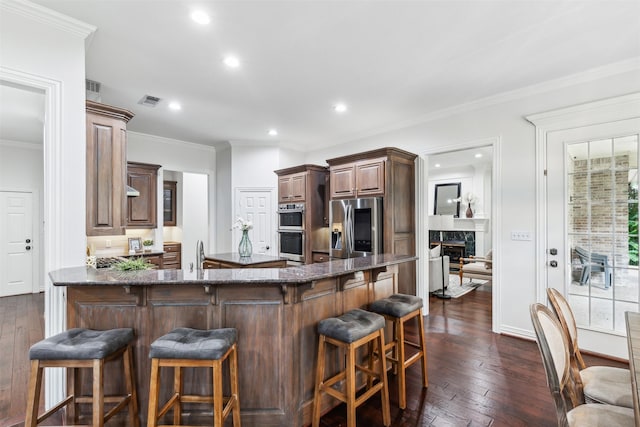 kitchen with a breakfast bar, kitchen peninsula, a fireplace, and appliances with stainless steel finishes