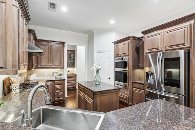 kitchen featuring sink, stainless steel appliances, range hood, crown molding, and dark stone counters