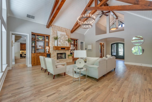 living room featuring beam ceiling, light hardwood / wood-style floors, a stone fireplace, and high vaulted ceiling