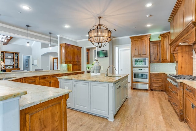 kitchen featuring appliances with stainless steel finishes, white cabinetry, pendant lighting, decorative backsplash, and a kitchen island with sink