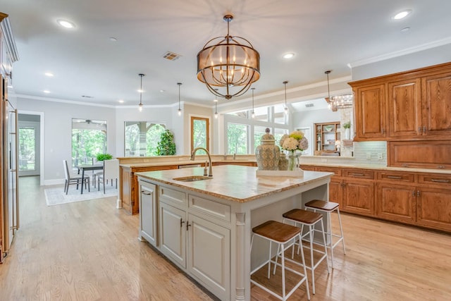 kitchen featuring light stone countertops, sink, a kitchen island with sink, and plenty of natural light