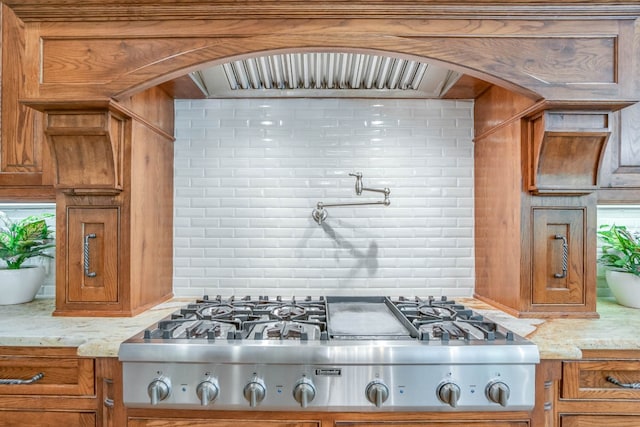 kitchen featuring stainless steel gas cooktop, decorative backsplash, and light stone countertops