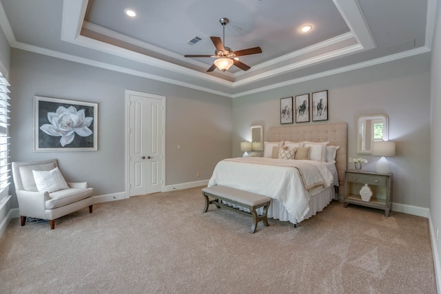 carpeted bedroom with ornamental molding, a tray ceiling, a closet, and ceiling fan