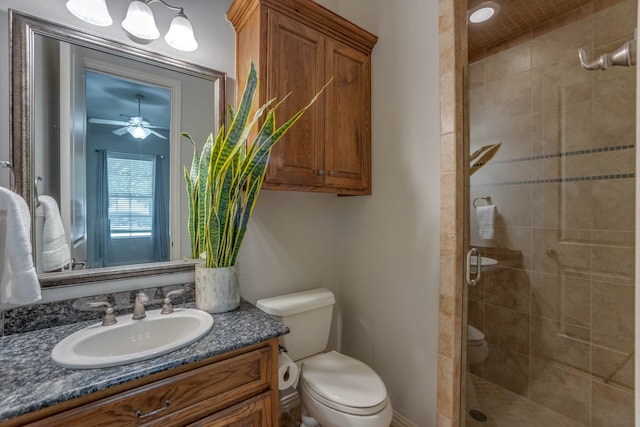 bathroom with vanity, toilet, a shower with shower door, and ceiling fan