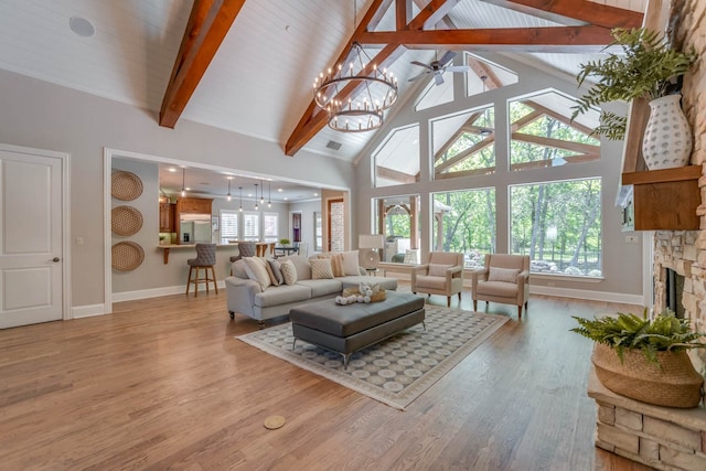 living room featuring wood ceiling, a stone fireplace, light hardwood / wood-style floors, beam ceiling, and high vaulted ceiling