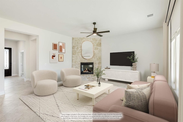 living room with plenty of natural light, ceiling fan, a stone fireplace, and light tile patterned floors