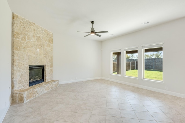 unfurnished living room with ceiling fan, a fireplace, and light tile patterned floors